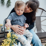 Maman avec son jeune garçon sur les genoux qui pointe des fleurs lors d'une mini-séance photo de Pâques